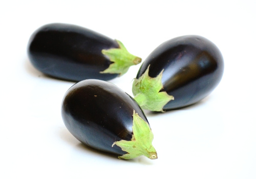 KI generiert: Drei dunkelviolette Auberginen auf weißem Hintergrund.