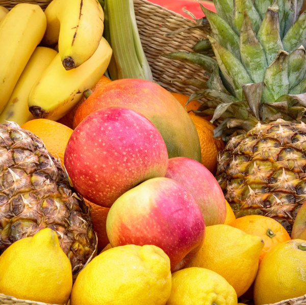 KI generiert: Ein Korb voller bunter Früchte, darunter Ananas, Bananen, Äpfel und Zitronen.