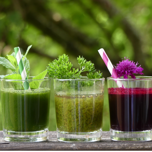 KI generiert: Drei bunte Smoothies in Gläsern mit Kräutern und Trinkhalmen.