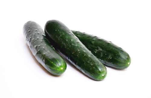 KI generiert: Drei frische Gurken liegen nebeneinander auf einem weißen Hintergrund.