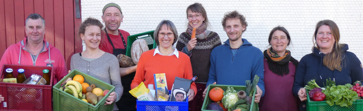 KI generiert: Acht Menschen halten Kisten mit Obst, Gemüse und Lebensmitteln.