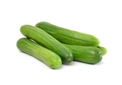 KI generiert: Fünf grüne Gurken liegen gestapelt auf weißem Hintergrund.